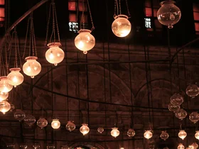 Viele Glühbirnen einer Deckenbeleuchtung in einem Theater, von denen einige ausgeschaltet oder defekt sind.