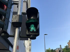 Das Foto zeigt eine auf Grün geschaltete Ampel in Mainz. Dort sind die Ampelanlagen für den Fußverkehr allerdings mit Signalen in Mainzelmännchen-Form statt in Kreisform wie sonst üblich versehen.